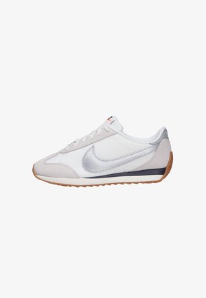 Chaussure de course Nike blanche et beige avec un logo argenté, une semelle couleur gomme et des lacets blancs, vue de profil sur un fond blanc.