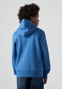 Μπλε βαμβακερή φούτερ με κουκούλα που κλείνει με κορδόνι, ριγωτούς μανίκια και στρίφωμα; διαθέτει λεία υφή και ένα μικρό λογότυπο στη κάτω αριστερή πλευρά.