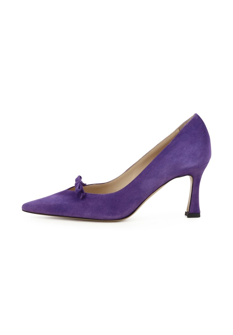 Scarpa con tacco alto in suede viola, con punta affusolata e piccolo fiocco decorativo nella parte anteriore. Il tacco è sottile e alto circa 7,5 cm.