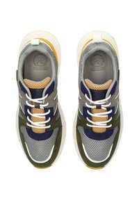 Las zapatillas presentan una combinación de malla gris, gamuza azul marino, acentos en verde oliva y una lengüeta de malla beige. Cuentan con cordones blancos gruesos y una suela amarilla.
