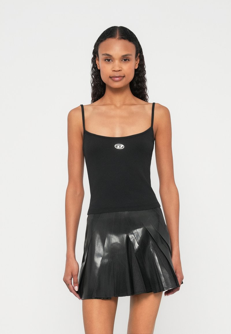 Čierny priliehavý top na ramienka s tenkými ramienkami a výstrihom do lodičky, zdobený malým logom v strede; v kombinácii s čiernou plisovanou minisukňou.