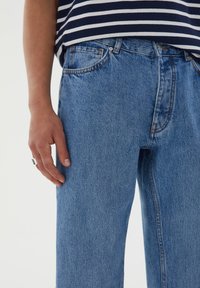 Ljusblå denimjeans med rak passform, som har en klassisk femfickorsdesign och synlig sömnad längs sömmarna.