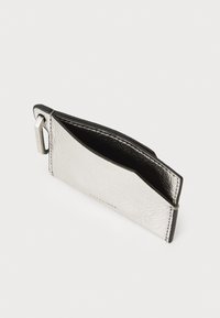 Portafoglio argento con texture, dotato di un interno nero, caratterizzato da un'apertura laterale e un accento in metallo argentato. Design minimalista con una finitura liscia.