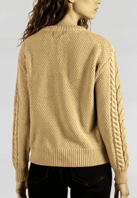 Suéter de punto beige con un patrón texturizado, dobladillo acanalado y mangas de trenzado. La vista trasera muestra el ajuste relajado del suéter.