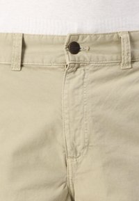 Beige cotton trousers featuring a front button closure, belt loops, and subtle stitching details. Smooth texture with a tailored design.