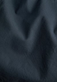 Tmavá látka s hladkým povrchem, obsahující jemné, diagonální žebrování. Barva je hluboká námořnická modř, s mírným leskem.