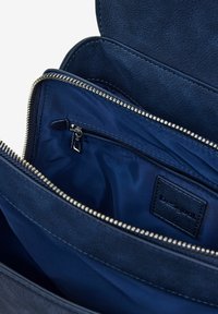 Navyblaue Ledertasche mit glatter Textur, die über ein Hauptfach und eine kleinere Reißverschlusstasche verfügt, silberne Reißverschlussdetails und ein Markenetikett.