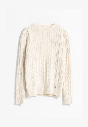Suéter de punto trenzado en color crema con cuello redondo, puños y dobladillo acanalados, que presenta un patrón texturizado y una pequeña etiqueta marrón en el lateral.