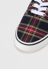 Tumesinised lõuendist tennised punaste, roheliste ja kollaste ruudumustriga. Omavad valgeid paelu ja tekstuuriga valget kummist põhja.