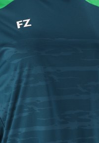 Tealblå træningsshirt med en grøn krave, subtile vandrette teksturmønstre og et hvidt "FZ" logo på den øverste venstre side.