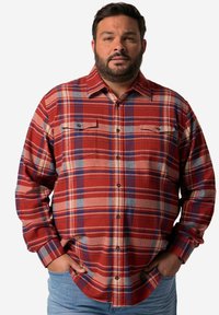 Camisa de cuadros en rojo y azul, con cuello, dos bolsillos en el pecho y un corte relajado con mangas largas. La tela parece suave.