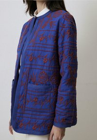 Blauwe geborduurde jas met bloemmotieven in roestkleur, met een rechte snit, lange mouwen en zijzakken. Gladde textuur.