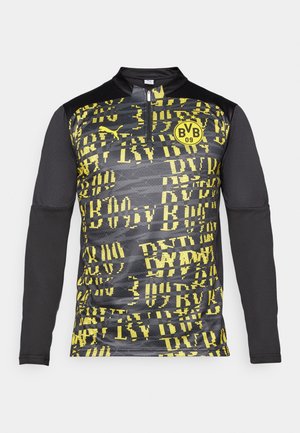 Langarm sportshirt met een zwart-geel grafisch patroon, ritskraag en logo op de voorkant, gemaakt van ademend materiaal.