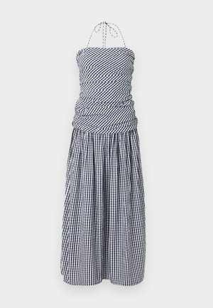 Črno-bela karo halter obleka z nabranim oprijetim korzetom in plisirano midi krilo na belem ozadju.