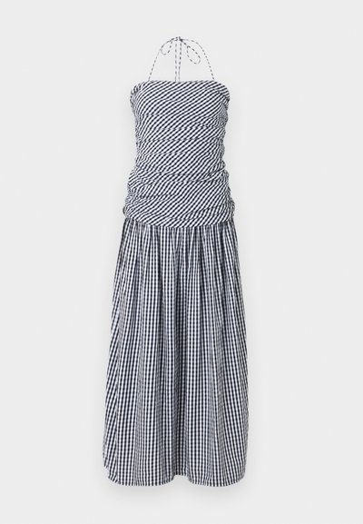 Μαύρο-άσπρο καρό φόρεμα με halter neck, με ραμμένο εφαρμοστό μπούστο και πλισέ midi φούστα σε λευκό φόντο.