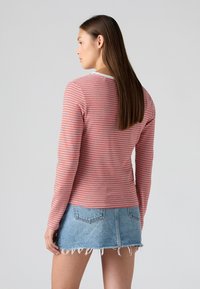 Röd och vit randig långärmad skjorta med rund halsringning, kombinerad med en blå denim minikjol med fransad nederkant.