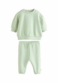 Pullover in cotone verde chiaro con maniche a sbuffo corte e polsini a coste, abbinato a pantaloni della tuta a gamba affusolata dello stesso colore con vita elasticizzata.