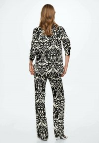 Set da lounge a fantasia bianco e nero composto da una maglia a maniche lunghe e pantaloni a gamba larga, caratterizzato da un intricato design a vortice e una consistenza morbida.