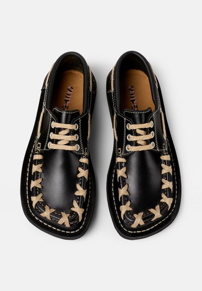 Scarpe in pelle nera con lacci beige e cuciture decorative. Design con punta quadrata, metallo a contrasto e superficie testurizzata. La suola è completamente nera.