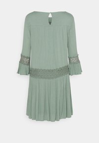 Vestido verde claro hecho de tela texturizada. Presenta mangas acampanadas con detalles de encaje, un escote con abertura en forma de ojo de cerradura y una falda fruncida.