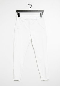 Bílé vypasované kalhoty zavěšené na černém ramínku. Mají boční kapsy a hladkou texturu bez viditelných vzorů či ozdob.