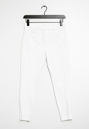 Pantalones blancos ajustados colgados en una percha negra. Incluye bolsillos laterales y una textura suave sin patrones o adornos visibles.