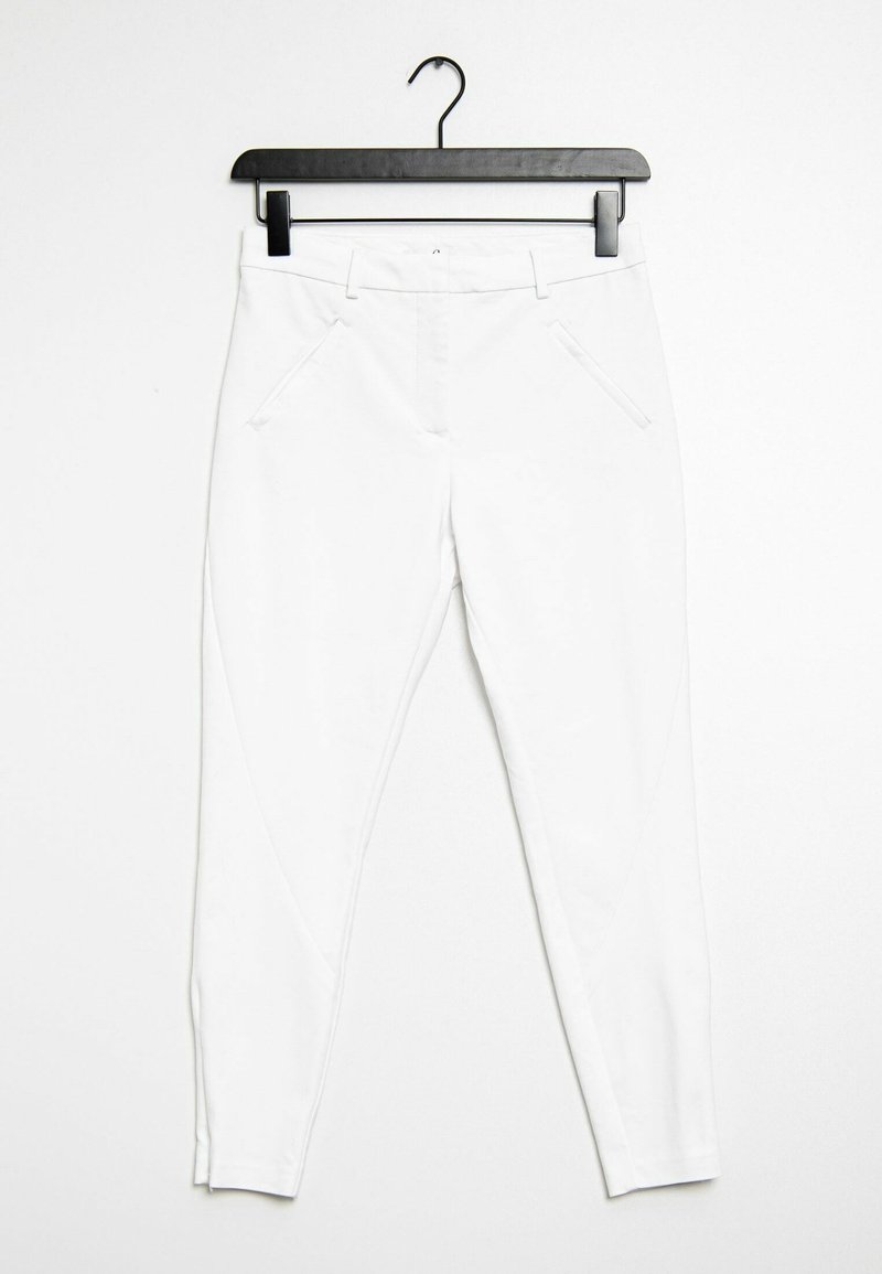 Bílé vypasované kalhoty zavěšené na černém ramínku. Mají boční kapsy a hladkou texturu bez viditelných vzorů či ozdob.
