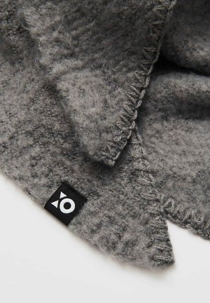 Grau gestrickter Wollschal mit strukturiertem Stoff, versehen mit einem markanten schwarzen Etikett mit weißem Emblem und sichtbaren Stichdetails an den Kanten.