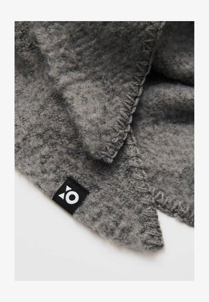 Sciarpa di lana grigia con tessuto testurizzato, caratterizzata da un'etichetta nera distintiva con un emblema bianco e dettagli di cucitura visibili lungo i bordi.