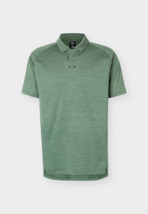 Polo verde de manga corta con cuello, textura jaspeada sutil, pequeño logo centrado debajo del escote y aberturas laterales en el dobladillo.