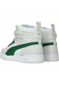 High-top sneakers with a white leather upper, green suede accents, padded collar, and a Velcro strap. Solid white rubber sole.