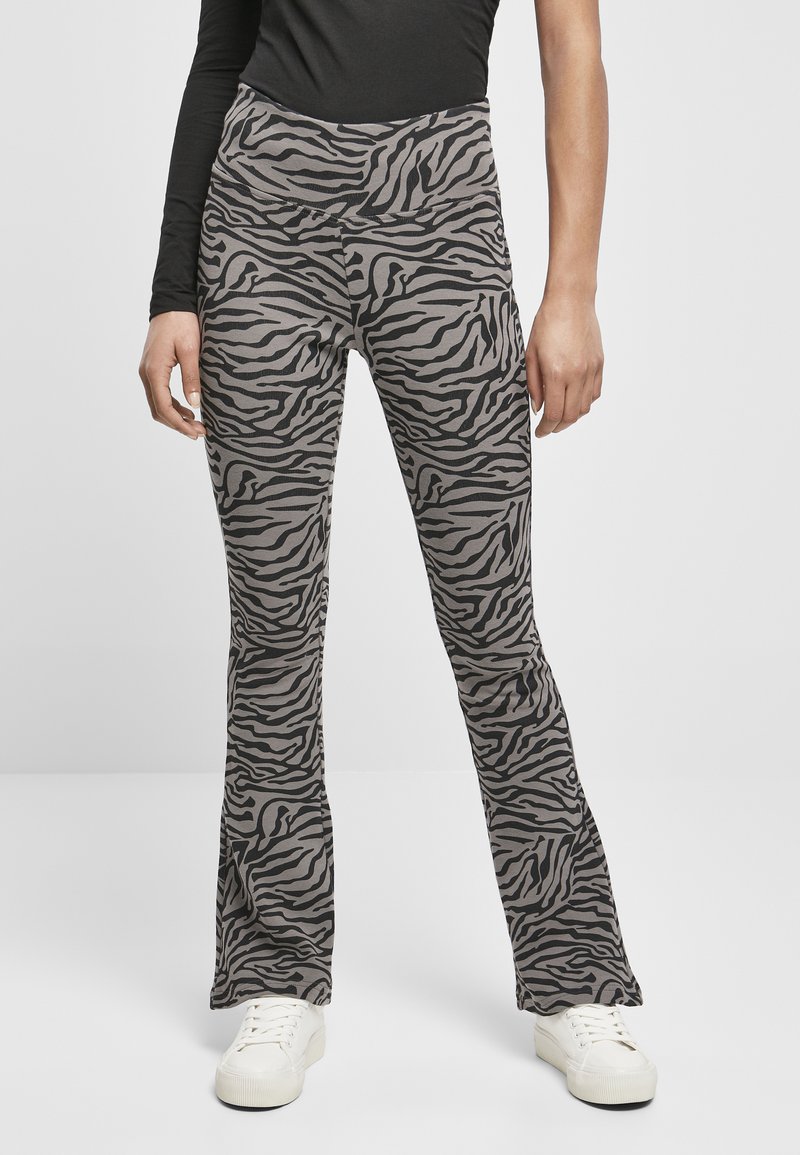 Pantaloni a zampa d'elefante in tessuto grigio chiaro con un motivo a righe zebra nere. Progettati con una vita alta e abbinati a sneakers bianche.