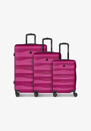 Trois valises rigides magenta avec des motifs ondulés, chacune avec quatre roues et des poignées télescopiques noires, présentées en petites, moyennes et grandes tailles.