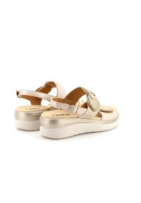 Sandali platform beige con cinturino alla caviglia regolabile. Parte superiore in pelle liscia con un accento decorativo in feltro. Presentano una suola metallica leggera.