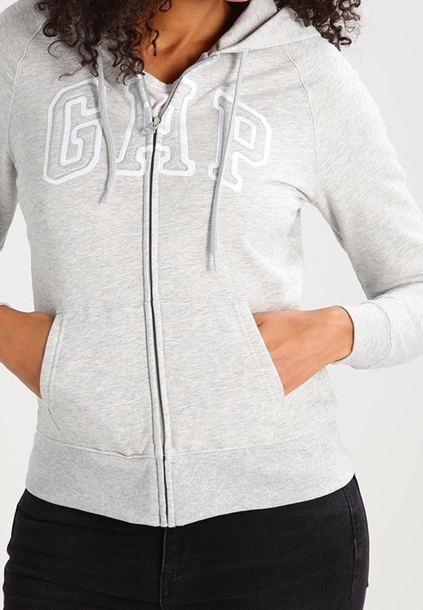 Felpa grigia con zip e texture morbida, caratterizzata da un grande logo bianco "GAP" sul petto e tasche a marsupio.