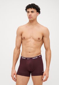 Vínové pánske boxerky s bielym logom Nike na elastickom pásku, hladká textúra a priliehavý dizajn.