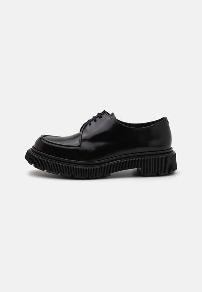 Chaussures noires en cuir verni à lacets avec un bout arrondi, semelle en caoutchouc épaisse et crantée, et des détails de couture discrets sur le dessus.