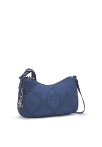 Blå quiltad crossbody-väska med justerbar rem, cirkulär logotyp-patch, silverdragkedja och en liten silverapa-hänge fäst.