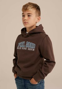 Ruskeat hupparit, joissa lukee "FEEL GOOD" ja "BLUE RIDGE DENIM". Pehmeä materiaali, istuva malli, jossa on kengurutasku ja ribbireunat.