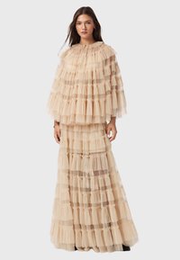 Φόρεμα από τούλι σε μπεζ απόχρωση με στρώσεις φρουρού, μακριά μανίκια και στρογγυλή λαιμόκοψη. Διαφανής υφή με οριζόντιες ρίγες ορατές. Σχεδίαση έως το πάτωμα.