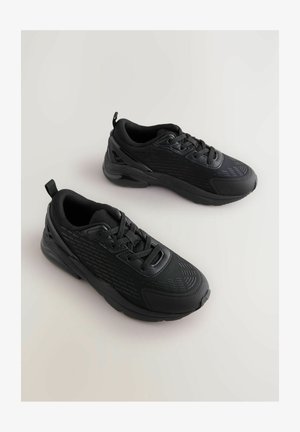 Svarta sportskor med strukturerad ovandel, vadderad tunga och kontrasterande glänsande detaljer. Gummisula med rundad tå och snörningssystem.