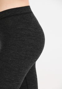 Högmidjade svarta leggings gjorda av textil, stretchigt material; har en slät midjeband och en åtsittande design. Inga synliga mönster eller dekorationer.