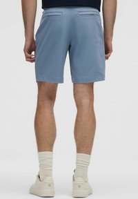 Heledad hallikas lühihaalaris valmistatud siledast kangast, tagakülgedel on taskud ja lõdva istumisega. Kanda koos valgete jooksujalatsitega ja kreemivärvi sokkidega.