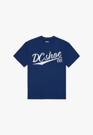 T-paita laivastonsinistä puuvillaa, jossa on suuri valkoinen graafinen logo "DCshoe Co." edessä, pyöreä pääntie ja lyhyet hihat.