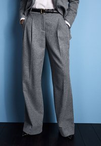 Gray wool trousers with a pleated front design, straight legs, and a cuffed hem, paired with a black belt and sleek shoes.