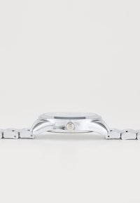 Montre en acier inoxydable argenté avec un boîtier rond, un verre plat et un bracelet à maillons. Dispose d'une couronne sur le côté pour régler l'heure.