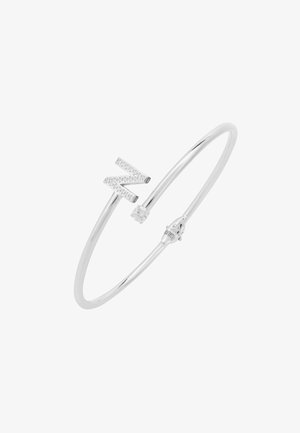 Sølv-armbånd med en slank struktur, der har et bogstav 'N' indlagt med diamanter og en rund ædelstensdetalje.