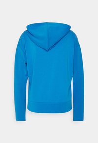 Modrá mikina s kapucí a volnějším střihem, dlouhými rukávy a texturovanou látkou. Zadní část bez švů a zakřivený spodní lem.