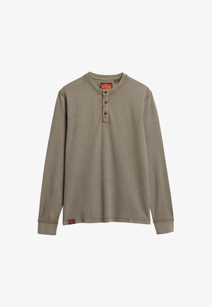 Maglietta henley a maniche lunghe in verde oliva smorzato, con scollatura rotonda, patta con tre bottoni e tessuto texture. Piccola etichetta del marchio sull'orlo.