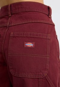 Marlboro crvene pamučne hlače s kontrastnim žutim šavovima, sa stražnjim džepovima i pravokutnom oznakom Dickies.
